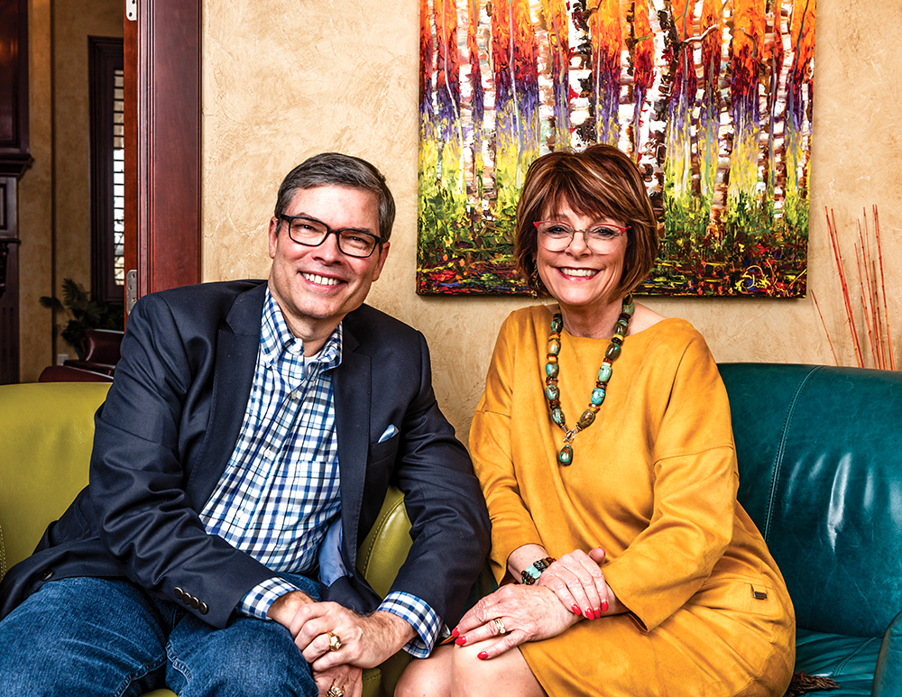 Dick and Lisa Pryor, one of Oklahoma’s best-known power couples, share a smile in front of part of a bold acrylic painting of a stand of aspens by Norman artist Tim Kenney.