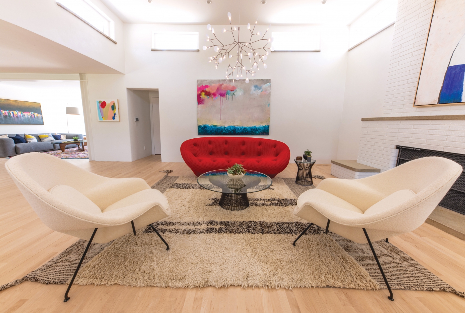 Clean shapes and bold design are seen throughout the Jones home. Here, a massive fireplace balances a lipstick red sofa, while neutrals underfoot provide a visual anchor.