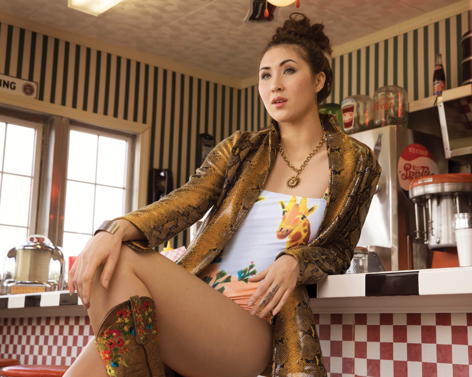 Carolina K. Kuna one-piece swimsuit from Gretta Sloane; Nasty Gal snakeskin jacket and Kendra Scott lion necklace from Library; Old Gringo cowgirl boots from Tener’s