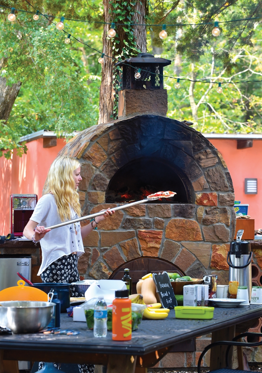 Britt Johnson fires up the outdoor oven to cook hand-tossed vegan pizzas for lunch.