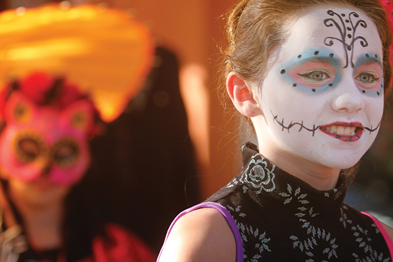 Costumed revelers promenade at a Day of the Dead festival.