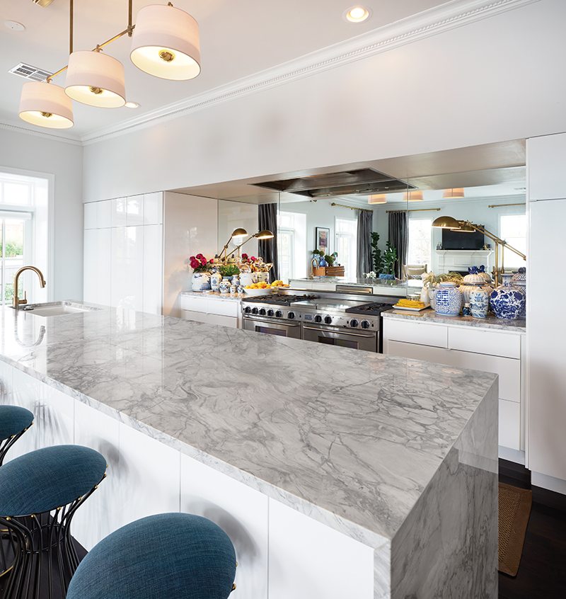 Barstools that easily could pass for Mid-Century vintage, but actually are standouts from West Elm, occupy one side of a massive, marble-topped island. Across the way, the kitchen has a range with some serious chops: a 60” commercial, FiveStar beauty. Cheery blue and white ginger jars and other Japanese vases add pops of clean color to the otherwise gray space.