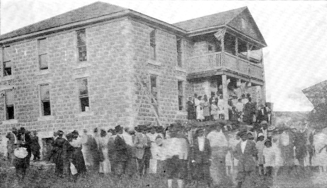 A grainy historical photo of Clearview, Oklahoma, shows a crowd of people around a large two-story building.