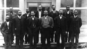 An historical photo of the town council of Boley, Oklahoma, posing in front of the town hall. Boley is currently the largest of the still existing historical All-Black towns in Oklahoma.