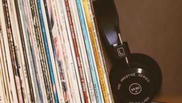 A pair of prestige headphones leans against a worn vertical stack of classical records.