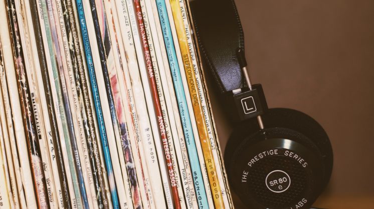 A pair of prestige headphones leans against a worn vertical stack of classical records.