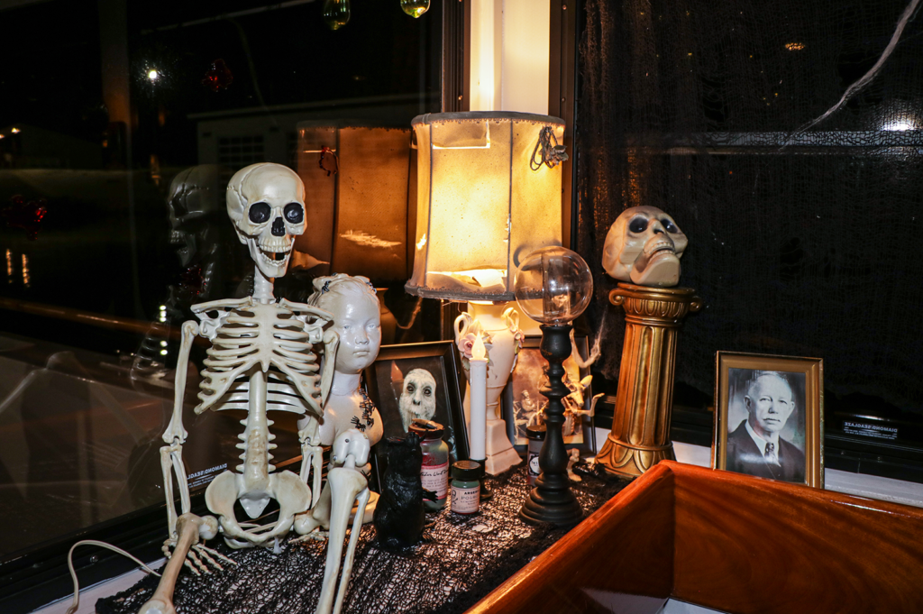 An assortment of spooky skeletons and eerie pictures and statues lean against the windows of an Oklahoma River Cruise ship.