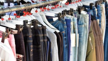Rows of pants hang from a thrift store rack.