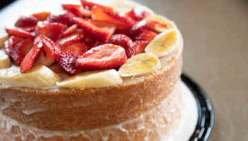 The strawberry and banana cake from Leo's BBQ, which features two layers of soft cake lined with sliced bananas on top and a pile of sliced strawberries.