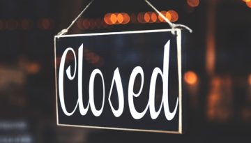 A sign hanging on a glass door reads "Closed."