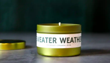 A small green candle that reads "Sweater Weather."
