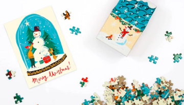 A box ornament that holds puzzle pieces that make up the image of a snow globe.