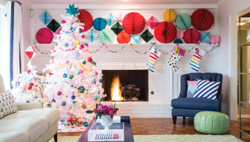 A white living room contains highlights of red, green, blue, orange and yellow circles, with a completely white Christmas tree decorated with ornaments of all colors and white stockings with rainbow stripes hanging on the fireplace.