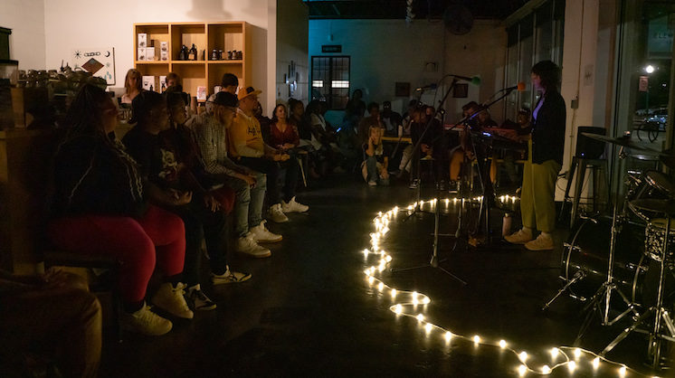 A small audience gathers around a band in a dimly lit coffee shop during a Sofar Sounds show in Oklahoma City.