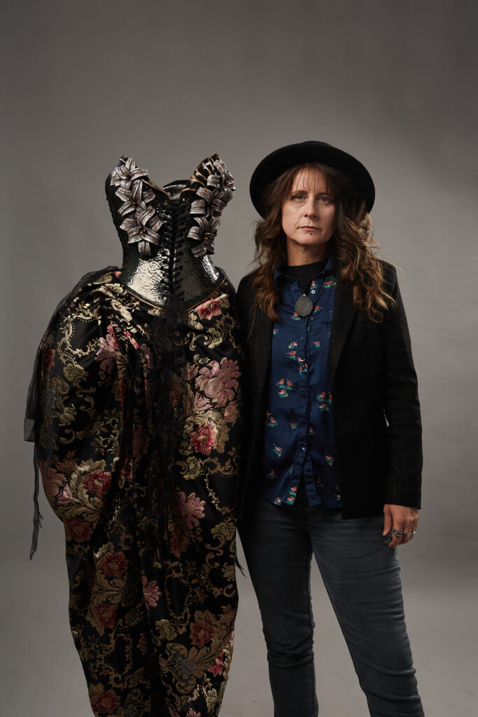 Ceramic artist Nicole Moan stands next to one of her ceramic corsets.