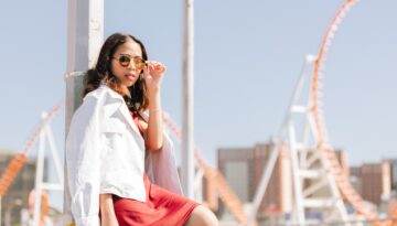 A woman with sunglasses sitting at a park in the summertime.