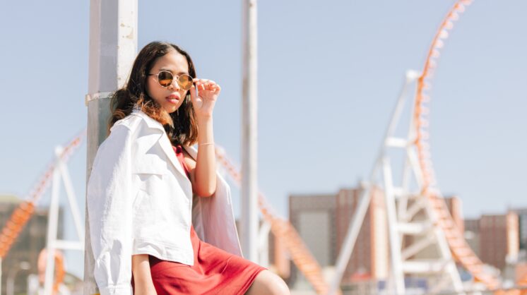 A woman with sunglasses sitting at a park in the summertime.
