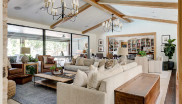 Living room with white oak beams, a tan couch and shaded chandeliers