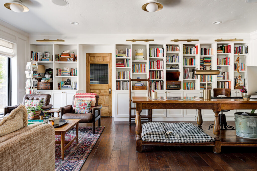 Seating area in an Edmond home with bookshelf embedded in wall, featuring heavy wooden furniture, leather chairs and an antique door
