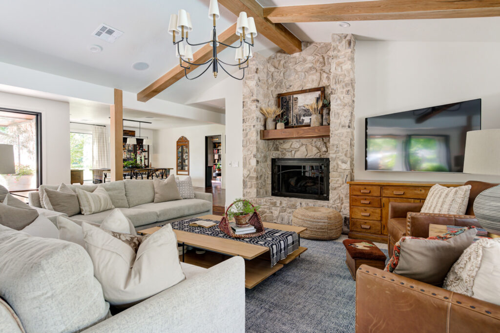 Photo of a living room in an Edmond home featuring large coffee table, fireplace made of embedded rocks, and chandelier.