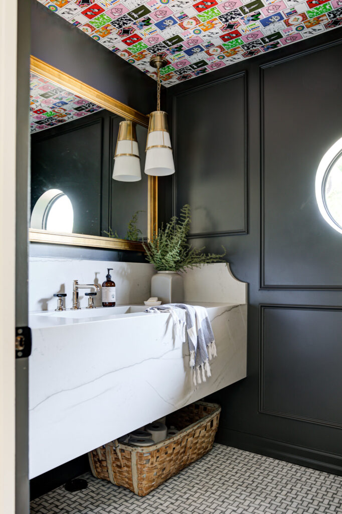 Black bathroom with gold mirror and playing card wallpaper on the ceiling