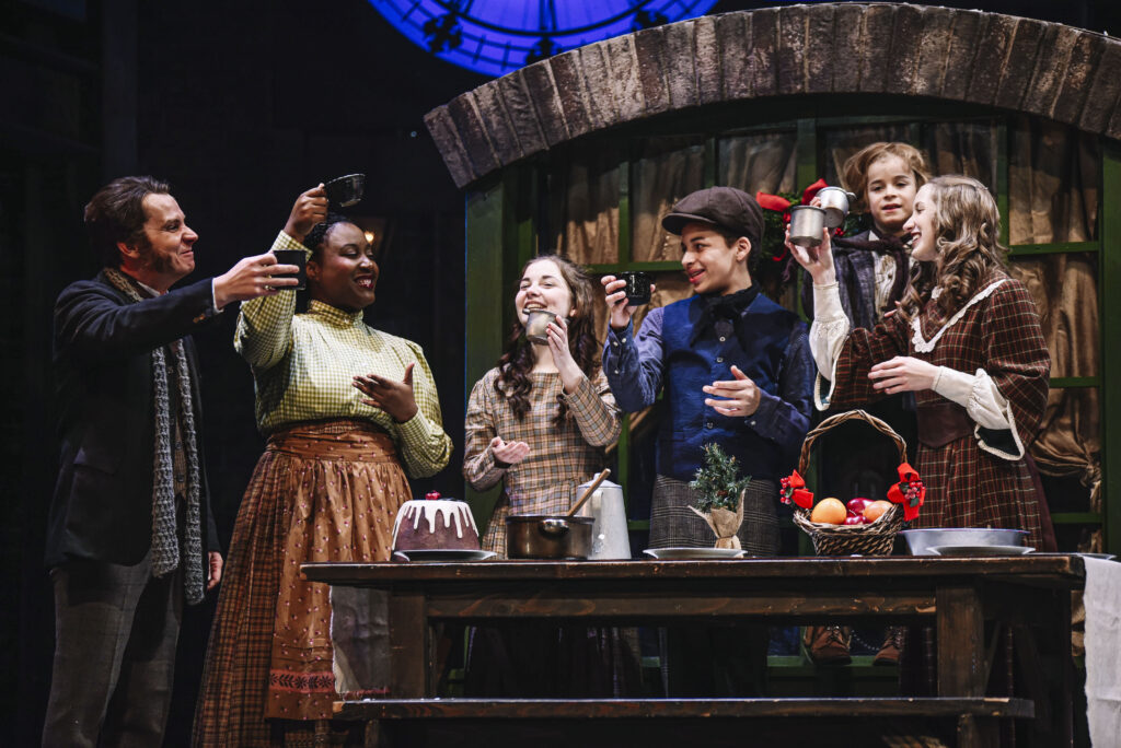 Group of actors surrounding a table at a production of the Christmas Carol