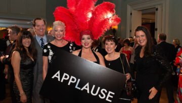 five people posing with a showgirl, who has on a headpiece of large red feathers