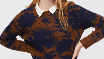Woman with red hair in an orange sweater with blue print