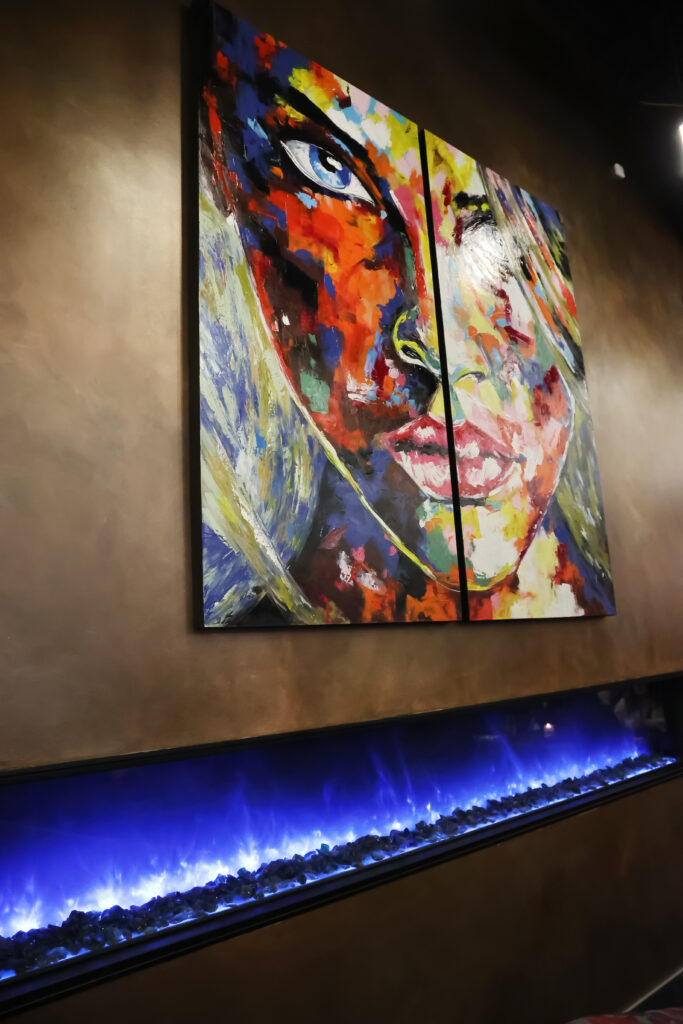 Colorful painting of a face above an electric fire place in Symmetry restaurant in OKC