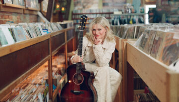 Ventriloquist Darci Lynne Farmer poses in a record store with a guitar