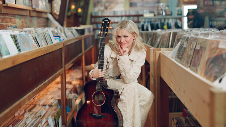Ventriloquist Darci Lynne Farmer poses in a record store with a guitar