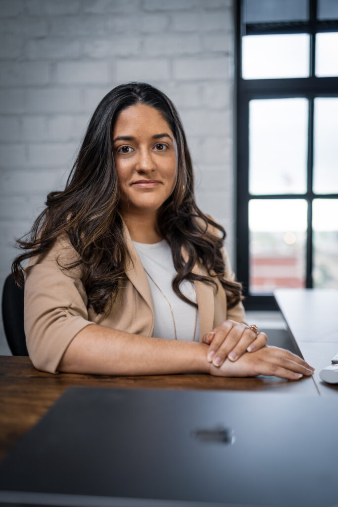 Ashley Quintana poses at her desk with a slight smile.