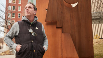 Oklahoma artist Klint Schor standing in front of his Downtown OKC Sculpture titled "The Kiss". Photographed by Charlie Neuenschwander.
