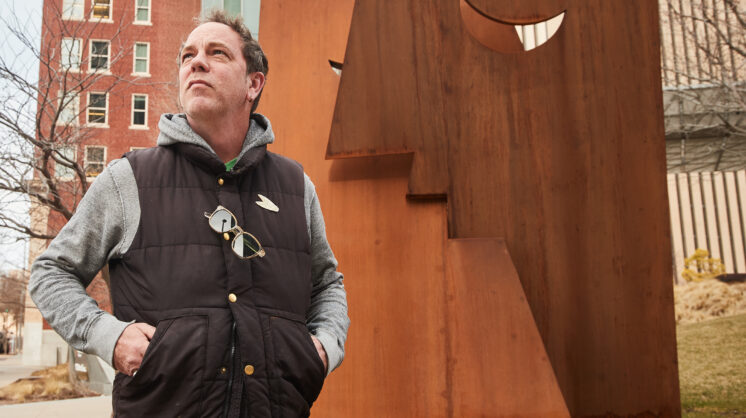 Oklahoma artist Klint Schor standing in front of his Downtown OKC Sculpture titled "The Kiss". Photographed by Charlie Neuenschwander.